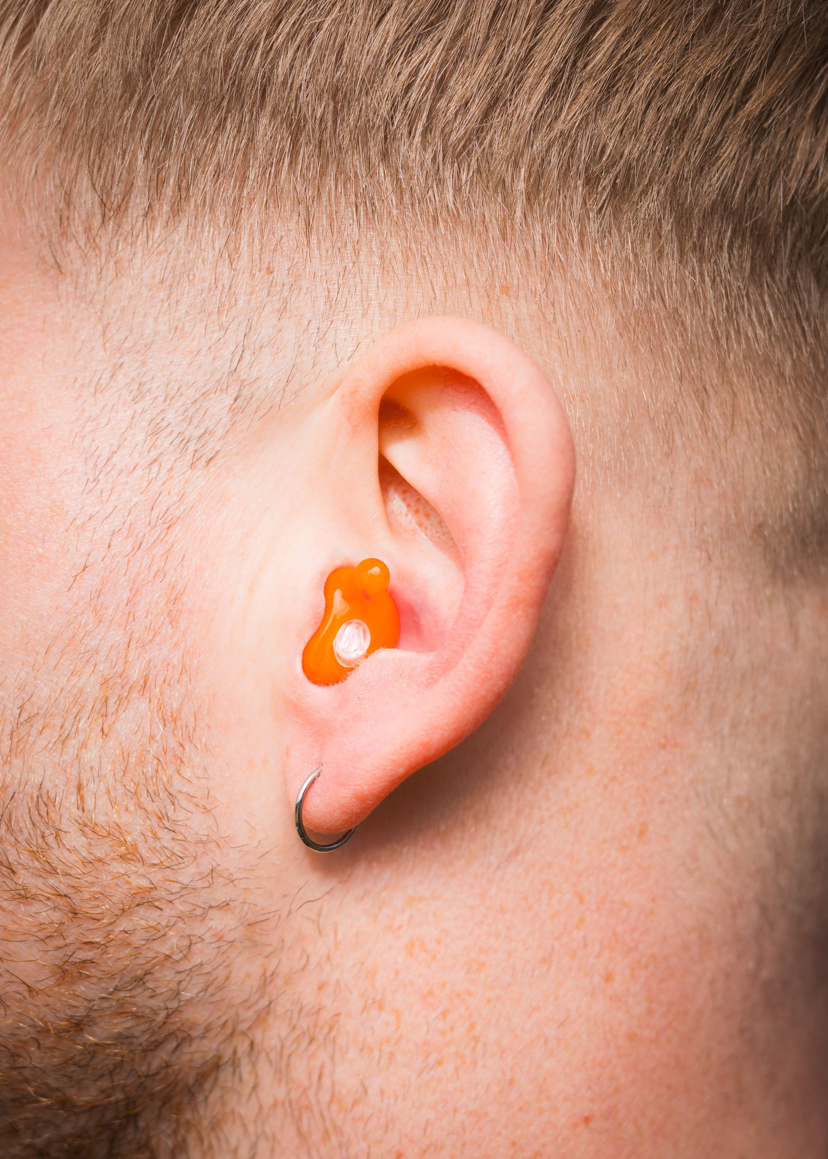 Alpine MusicSafe Custom earplug worn in the ear, close-up of a man with short hair