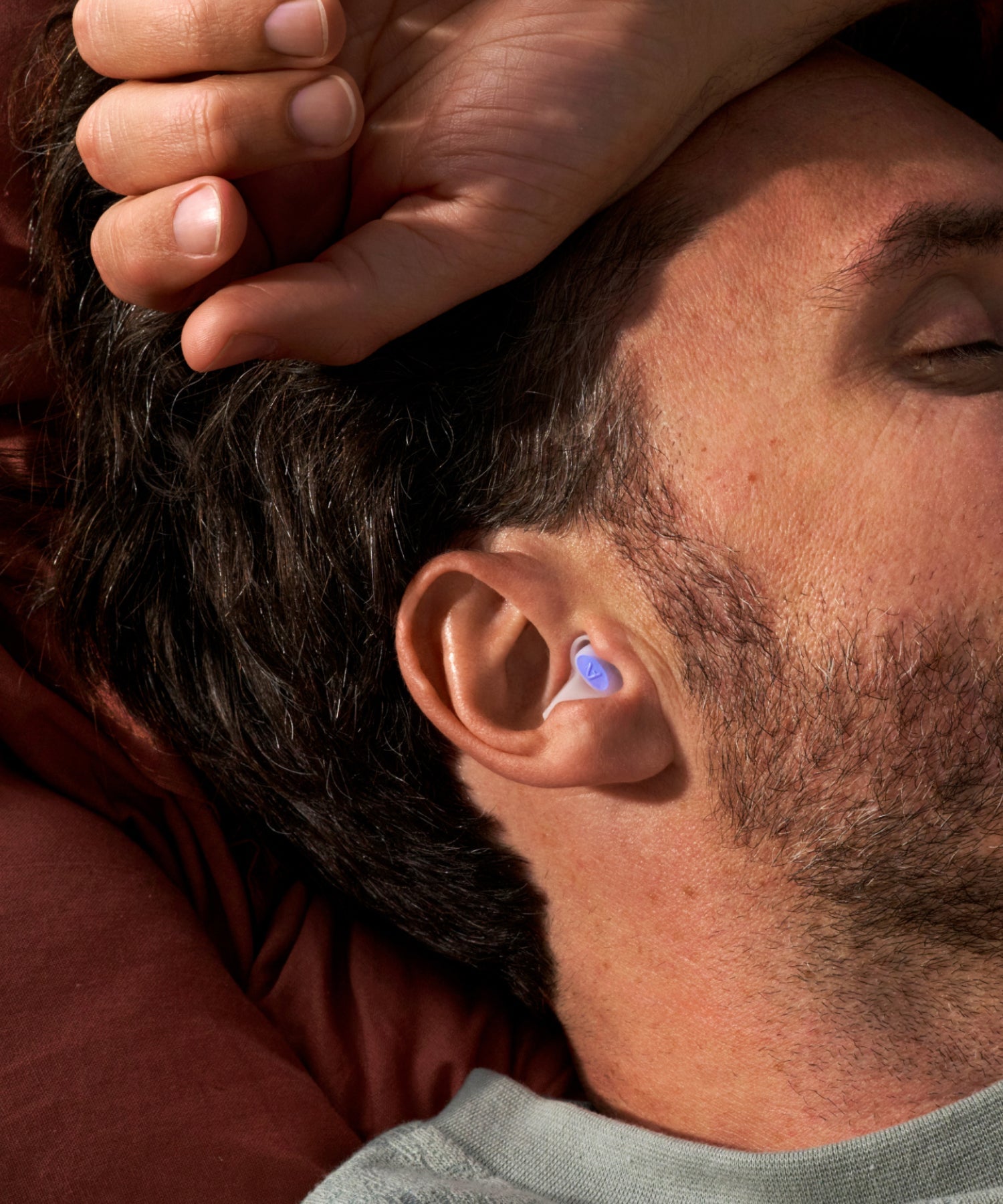 Alpine SleepDeep earplug worn by a man sleeping on a pillow