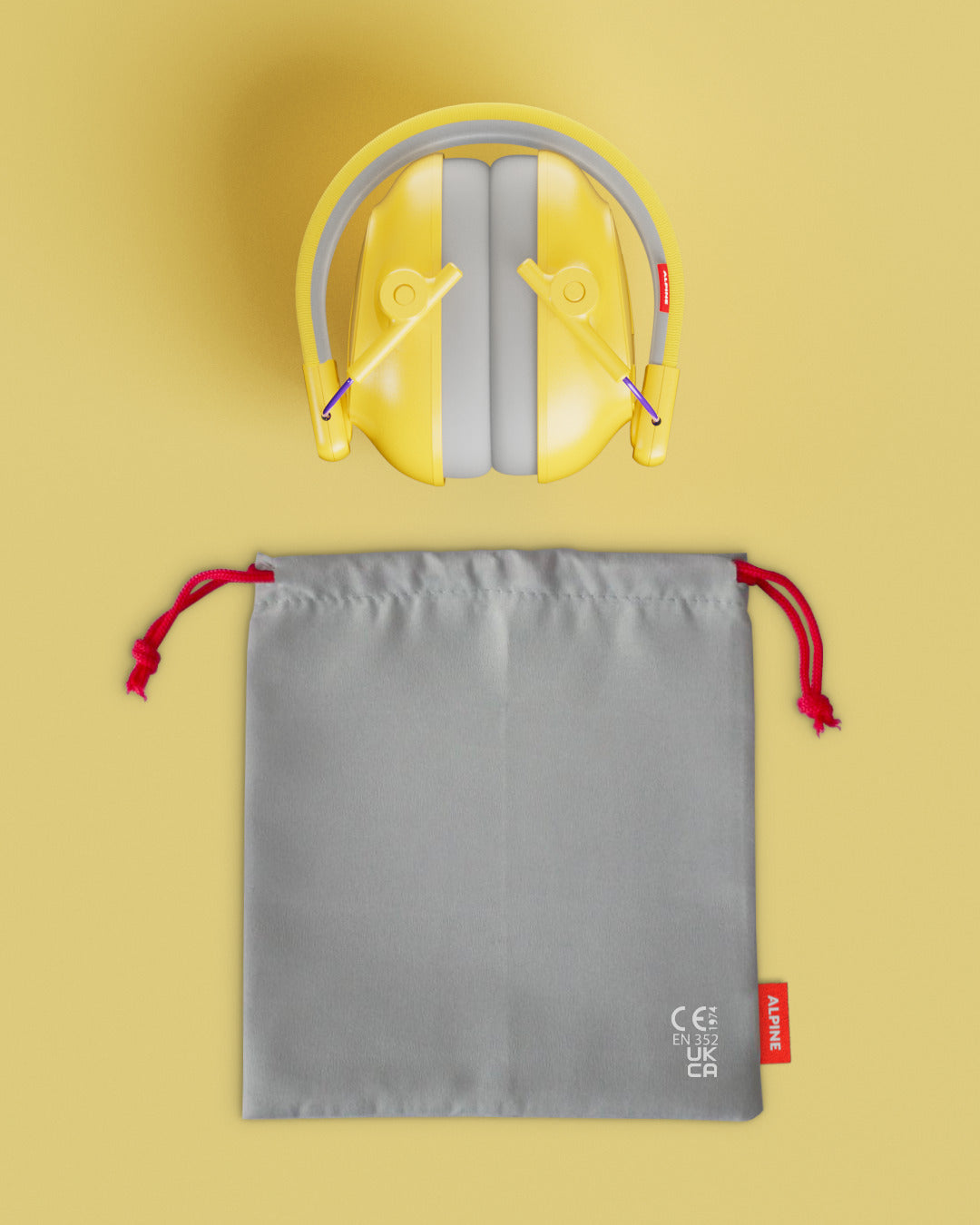 Alpine Muffy Baby ear defenders in yellow, folded, with grey carrying pouch 